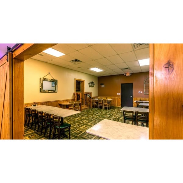 Mi Casa Mexican Restaurant's dining room with multiple tables and chairs, wood paneling, and patterned carpet.