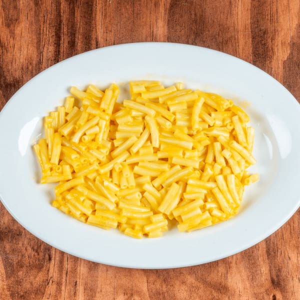 A white oval plate filled with creamy yellow macaroni and cheese on a wooden table.