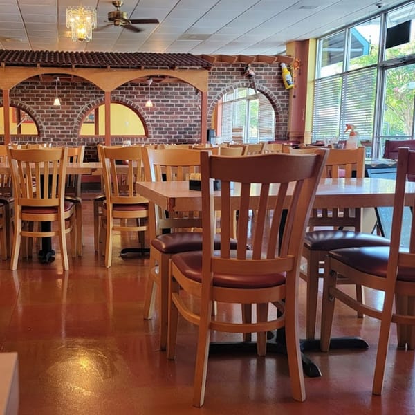 Interior of Mi Casa Mexican Restaurant with empty tables and chairs, brick arches, and large windows.