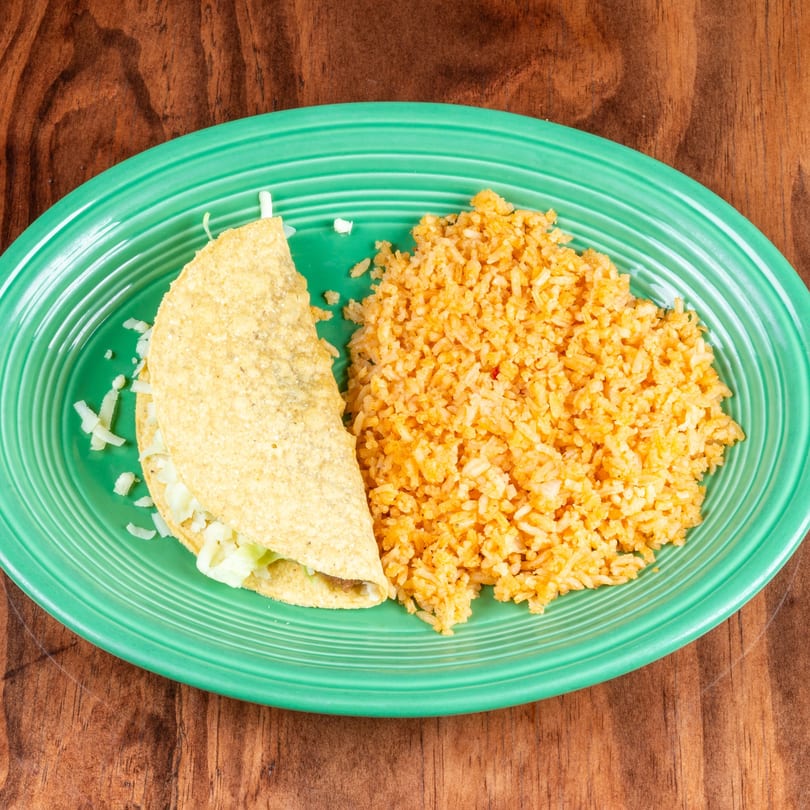 A crispy taco filled with lettuce and cheese, served with a side of orange rice on a green plate.